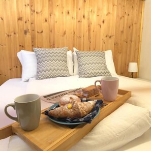 A bed with wooden headboard, pillows, a tray with a mug, a plate with pastries, and a newspaper. - Orio welcome BGY (Bergamo)