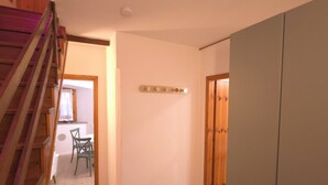 A hallway with wooden flooring, a staircase, a dining area with chairs, and a wardrobe. - Orio welcome BGY (Bergamo)