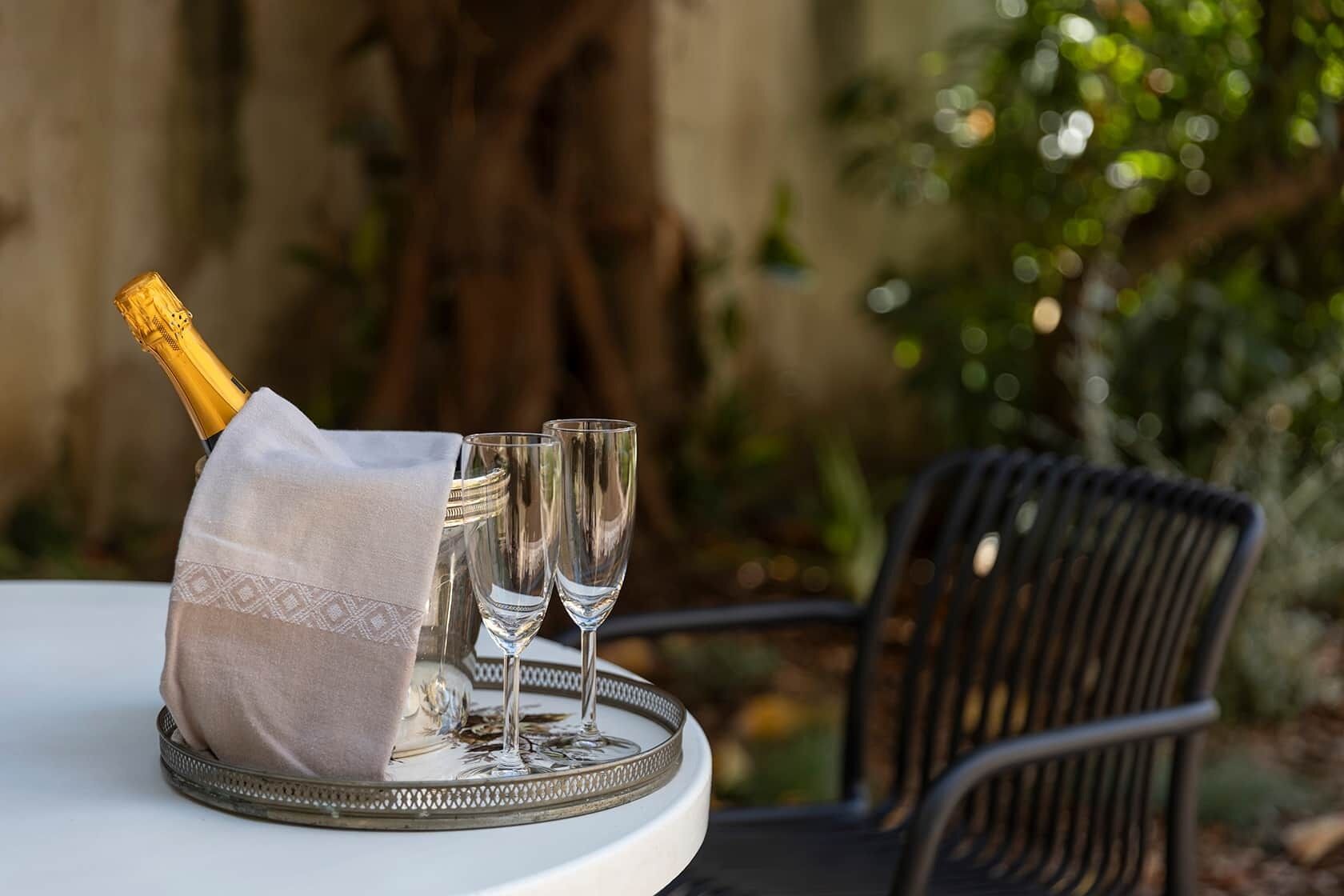 Una mesa con una botella de champán, dos copas y un paño decorativo.