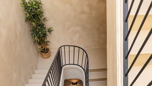 Un escalier en colimaçon avec une rampe et un pot de fleurs placé à côté.