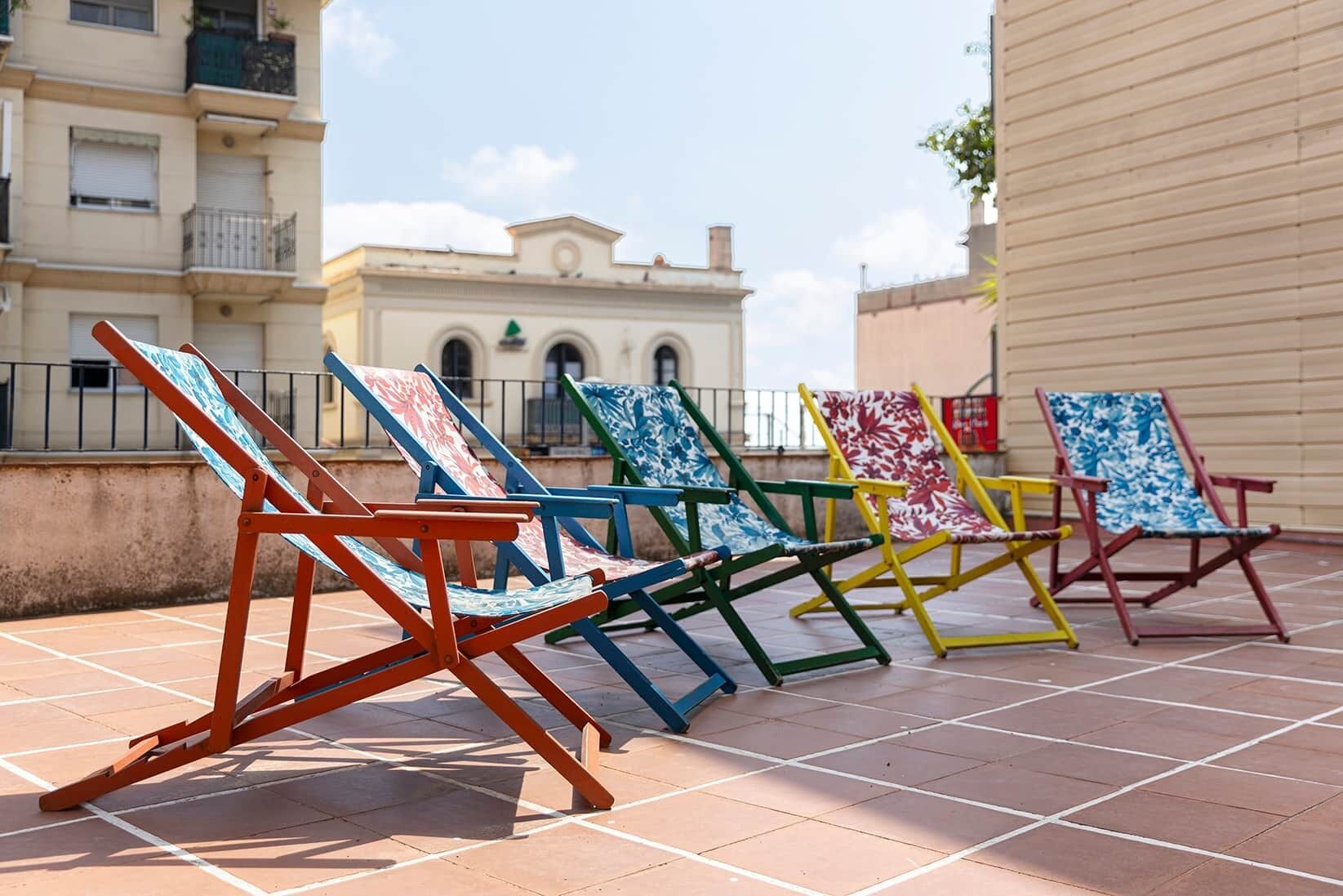 Outdoor patio chairs with a tiled floor and a building in the background.