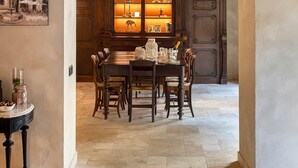 Ein Essbereich mit Tisch und Stühlen, einem Holzschrank mit Glastüren und einem Gemälde an der Wand.
