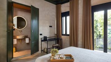 Une chambre d’hôtel avec un lit, une salle de bain avec un miroir, un bureau et une vue sur la verdure.