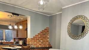 Una sala de estar moderna con un sofá, una mesa de centro, un comedor con sillas, una cocina con pared de ladrillo y una escalera.