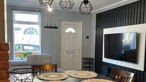 Un comedor con una mesa de madera, sillas y un televisor montado en la pared.