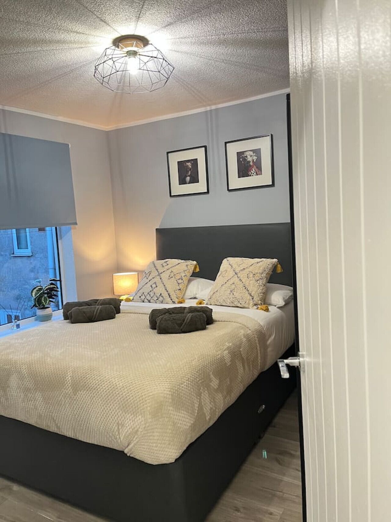Un dormitorio moderno con una cama, lámparas de noche y cuadros en la pared.