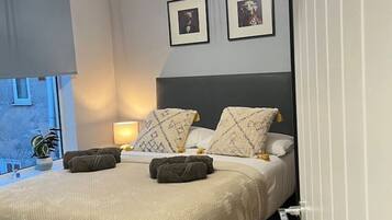 Un dormitorio moderno con una cama, lámparas de noche y cuadros en la pared.