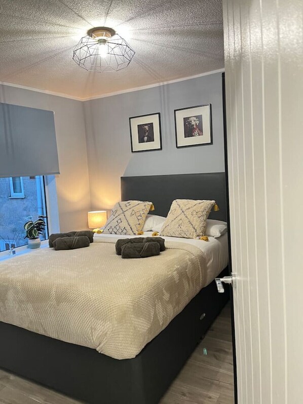 A modern bedroom with a bed, bedside lamps, and framed pictures on the wall.
