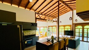 A spacious kitchen with a large island, a dining area with chairs, a TV, and a view through large windows. - Private Countryside Retreat Jacuzzi & Scenic View (pereira)