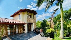 A two-story house with a stone facade, a tiled roof, and a paved patio. - Private Countryside Retreat Jacuzzi & Scenic View (pereira)