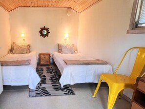 A small room with two beds, a nightstand, a mirror, a sun decoration, a zebra-patterned rug, and a yellow chair. - 4 Person Holiday Home in Holsljunga (Holsljunga)