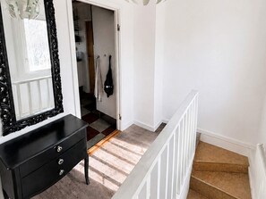 A staircase with a white railing, a black dresser with drawers, and a mirror with an ornate frame. - 4 Person Holiday Home in Holsljunga (Holsljunga)