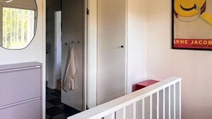 Un pasillo con una puerta blanca, una toalla colgada en la puerta y una escalera con barandilla blanca.