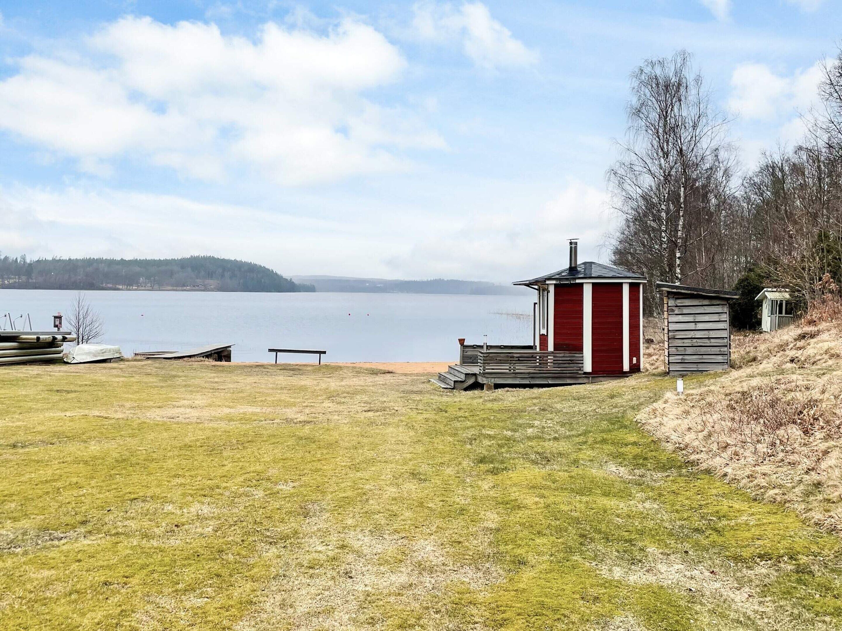 A lakeside cabin with a dock, a small shed, and a bench.