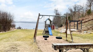 Un parque infantil con columpios, neumáticos colgantes y un tobogán.