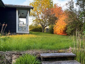 A house with a porch, a grassy yard, and a tree with autumn leaves. - 5 Person Holiday Home in Holsljunga (Holsljunga)