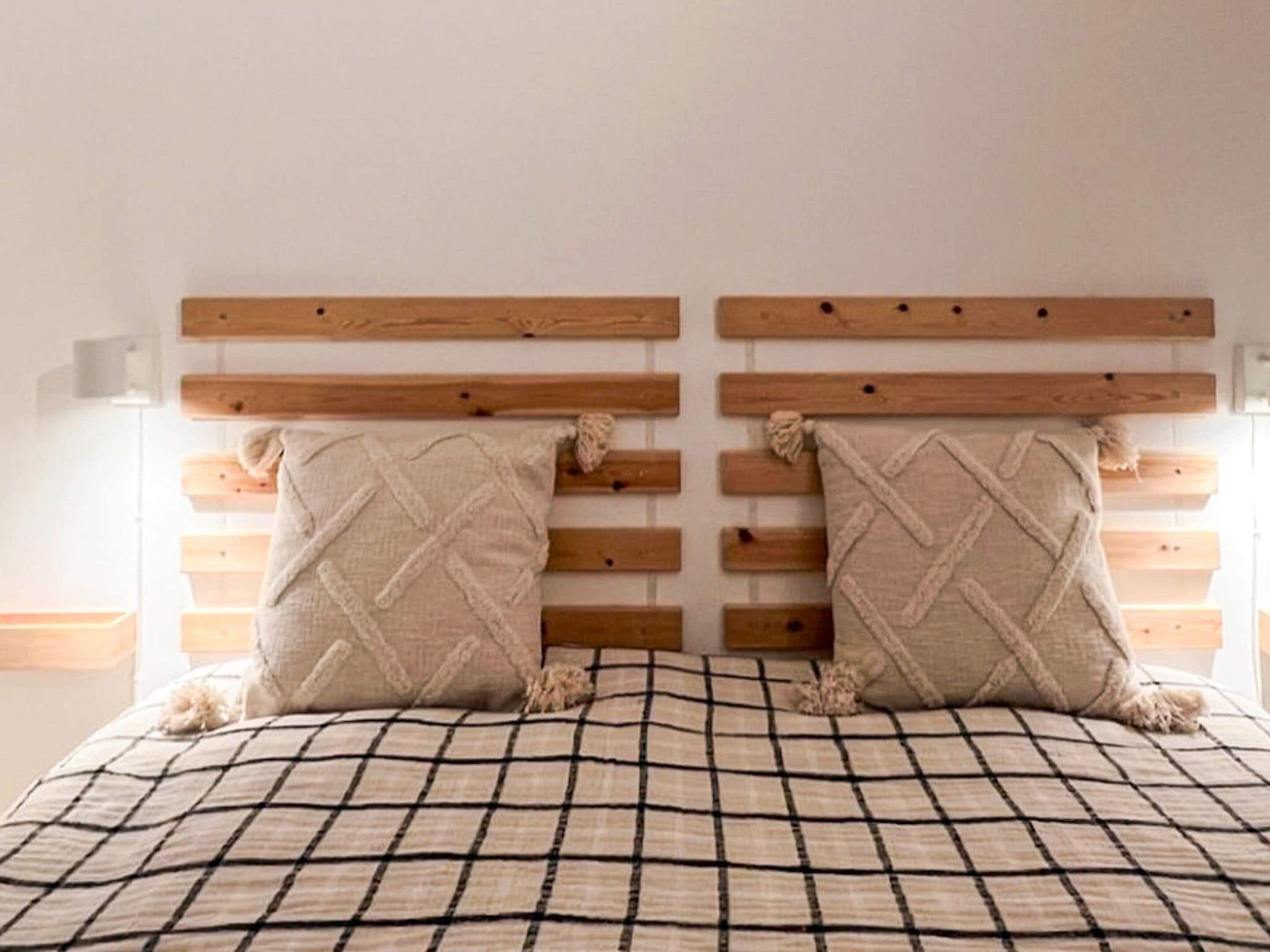 A bed with a checkered bedspread, two pillows with a diamond pattern, and a wooden headboard with horizontal slats.