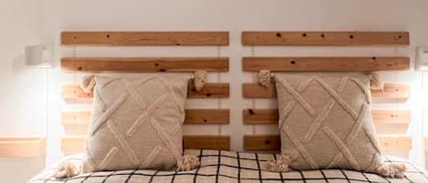 A bed with a checkered bedspread, two pillows with a diamond pattern, and a wooden headboard with horizontal slats.