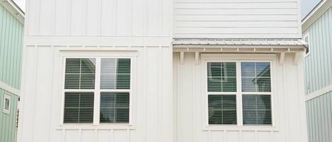 Une maison à deux étages avec un garage, une véranda et un petit espace extérieur aménagé pour s’asseoir.