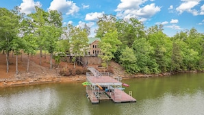 A dock with a boat, a building, and a forested area. - Spacious 5 bedroom house with double decker dock on quiet lakefront! (Arley)