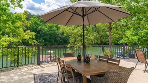 An outdoor patio with a table, chairs, an umbrella, and a view of a lake. - Spacious 5 bedroom house with double decker dock on quiet lakefront! (Arley)