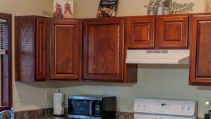 Una cocina con armarios de madera, microondas, estufa y encimera de granito.