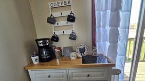 Una encimera de cocina con una cafetera, tazas y un letrero con temática de café.