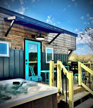 A wooden cabin with a hot tub, outdoor seating, and a deck. - Tiny home on the Upper iowa river (Dorchester)