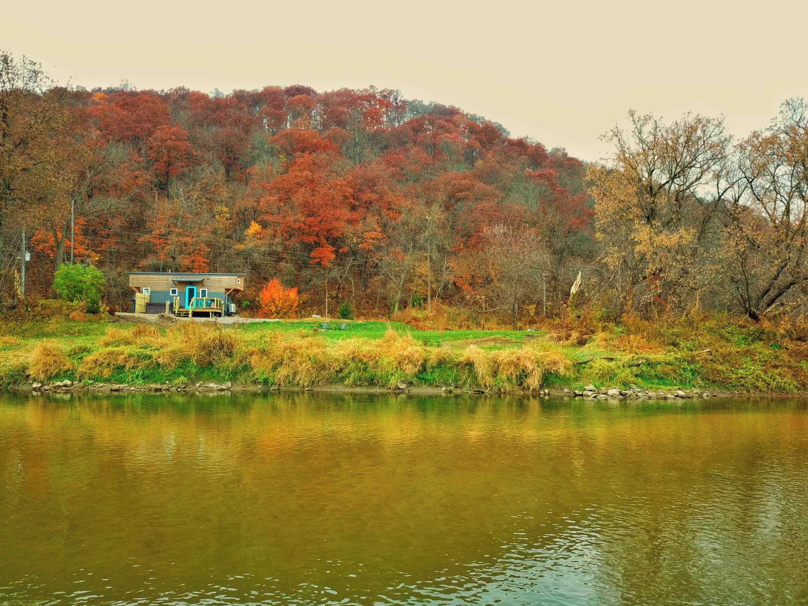 A house by a lake with a forested hill in the background.