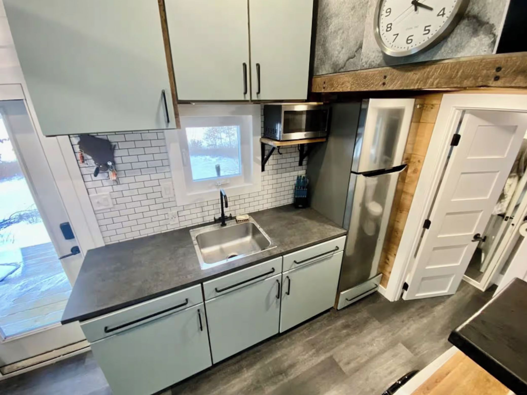 A kitchen with a sink, cabinets, a microwave, and a refrigerator.