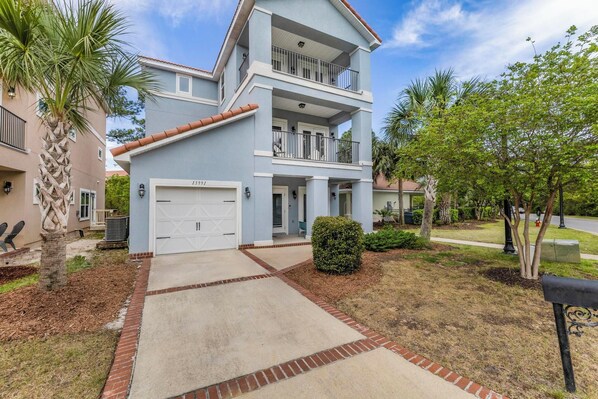 A two-story residential building with a garage, a balcony, and a well-maintained lawn.