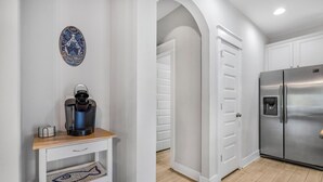 Eine Küche mit weißen Schränken, einem Edelstahlkühlschrank und einer Kaffeemaschine auf einem Holzboden.