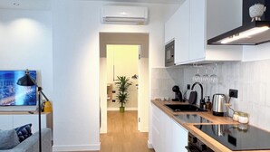 A modern kitchen with a wooden countertop, a built-in oven, and a microwave. There is a potted plant and a small table with a lamp. - April Suites Apartments - Suite 1, Amber (Palermo)