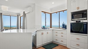 A modern kitchen with white cabinetry, a built-in oven, and a view of the beach. - Marina by the Sea | Ocean Reef Luxury 4 Bed + study | Marina & Ocean Views (Ocean Reef)