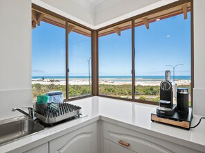A kitchen with a view of the beach, a coffee maker, and a dish rack. - Marina by the Sea | Ocean Reef Luxury 4 Bed + study | Marina & Ocean Views (Ocean Reef)