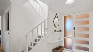 A staircase with white railings, a wall-mounted mirror, and a door with frosted glass panels. - Marina by the Sea | Ocean Reef Luxury 4 Bed + study | Marina & Ocean Views (Ocean Reef)