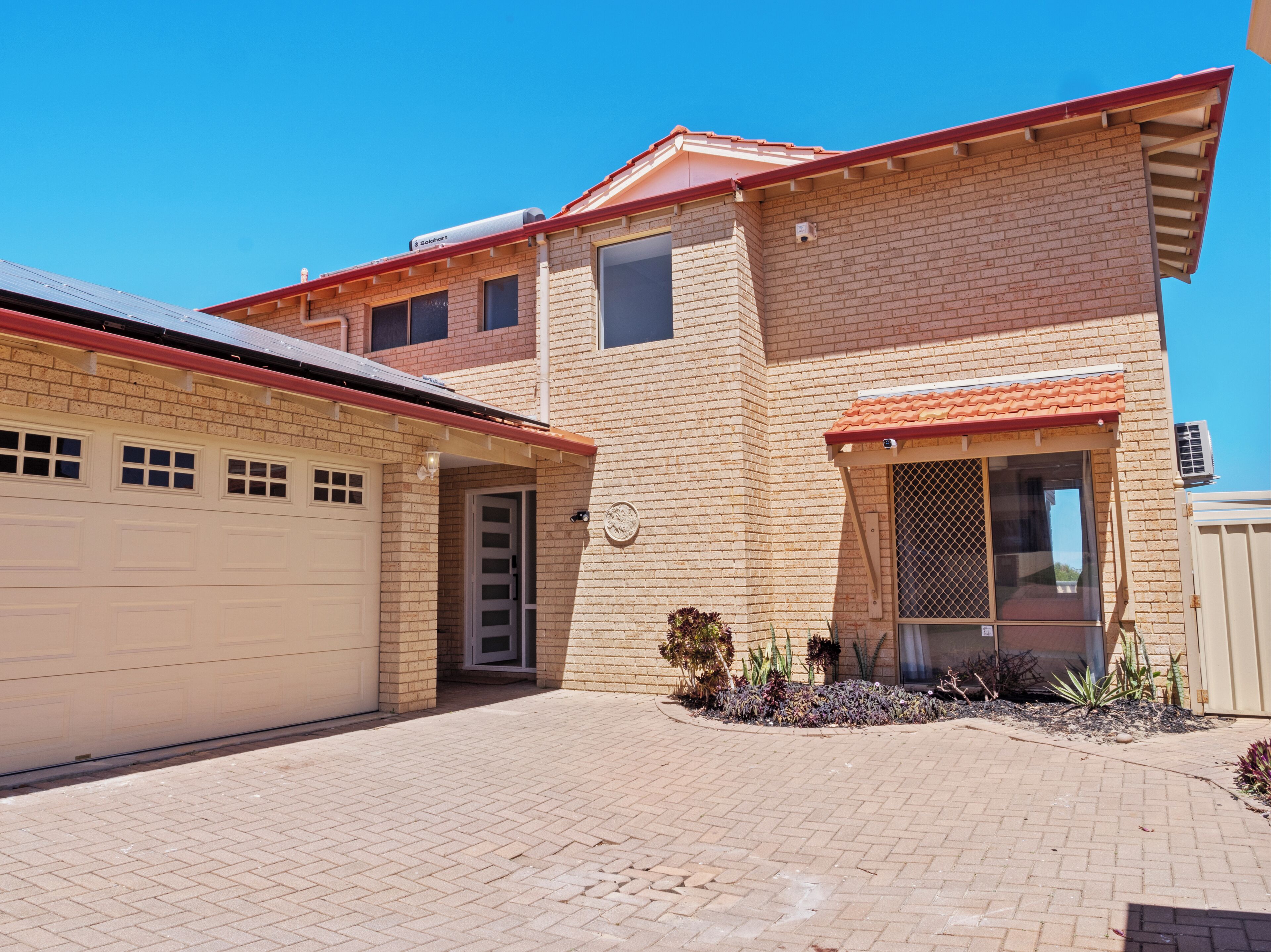 A two-story house with a garage, a covered patio, and a small garden area.