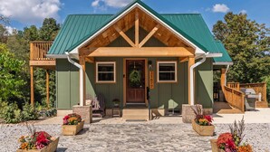 A lodge with a green roof, wooden exterior, and a front porch with flower planters. - Bear's Den (Washington Township)