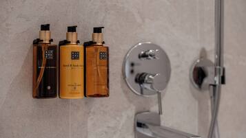 Tres lociones corporales y para manos Rituals sobre un estante fijado a la pared, junto a una ducha.