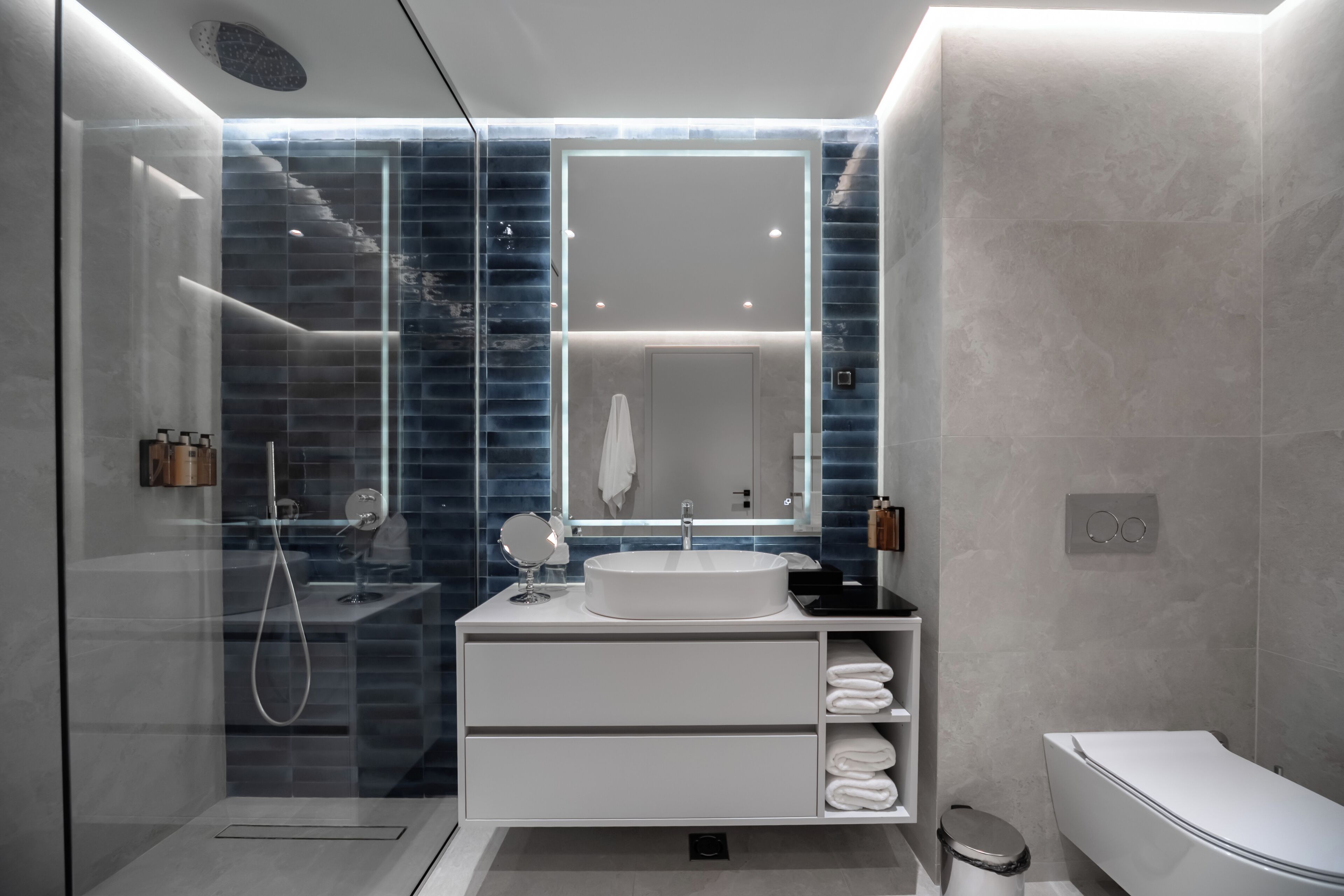 A modern bathroom with a glass-enclosed shower, a white vanity with a sink, and a toilet.