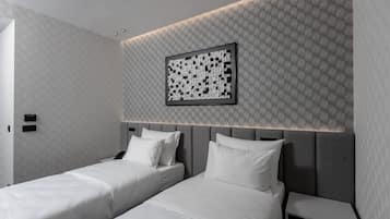 Una habitación de hotel moderna con dos camas, un cabecero con iluminación integrada, una obra de arte colgada en la pared y una mesita de noche.