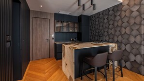 A modern kitchen with a central island, dark cabinetry, and a patterned wall. - Hotel Cube (Bar)