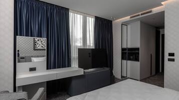 A modern hotel room with a bed, a desk, a TV, and a wardrobe.
