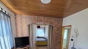 Ein modernes Wohnzimmer mit Fernseher, Sofa und einer Ziegelwand.