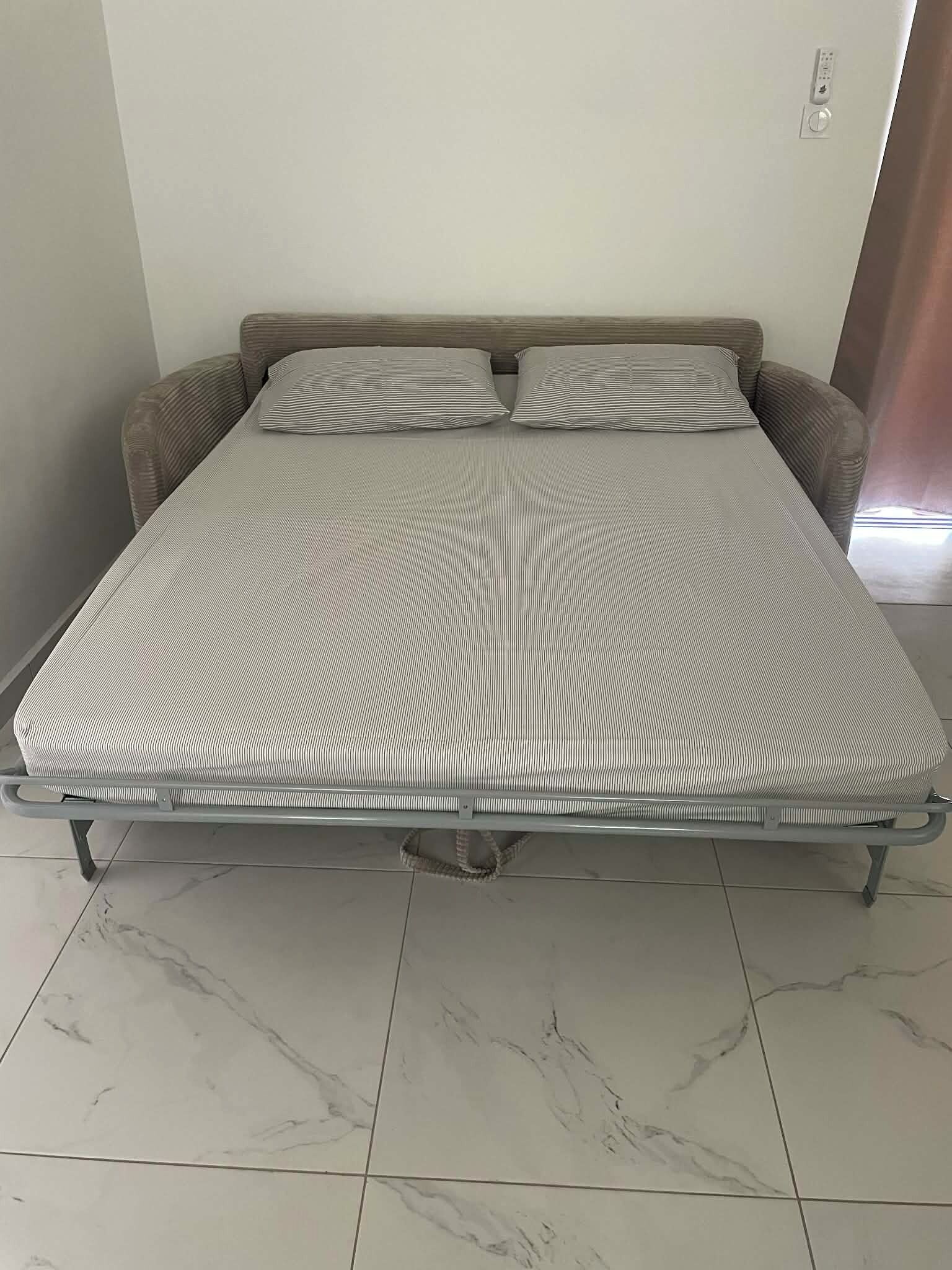 A bed with a striped mattress, a headboard, and a metal frame.