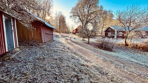 Une route de campagne bordée de bâtiments en bois, un ciel dégagé et un paysage hivernal.