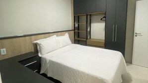 Ein Schlafzimmer mit einem Bett, einem Schrank, einem Schreibtisch und einem weiteren Schrank mit Spiegel.