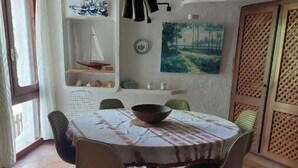 A dining area with a round table, chairs, a bowl, and a painting on the wall.