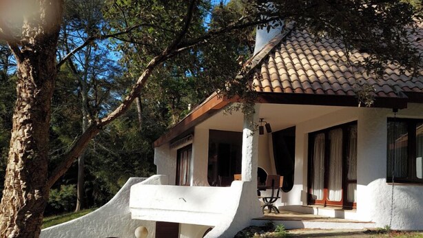 A house with a sloped roof, white exterior walls, and a wooden deck.