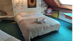 A bedroom with a bed, a wall-mounted light fixture, a painting, and a skylight.